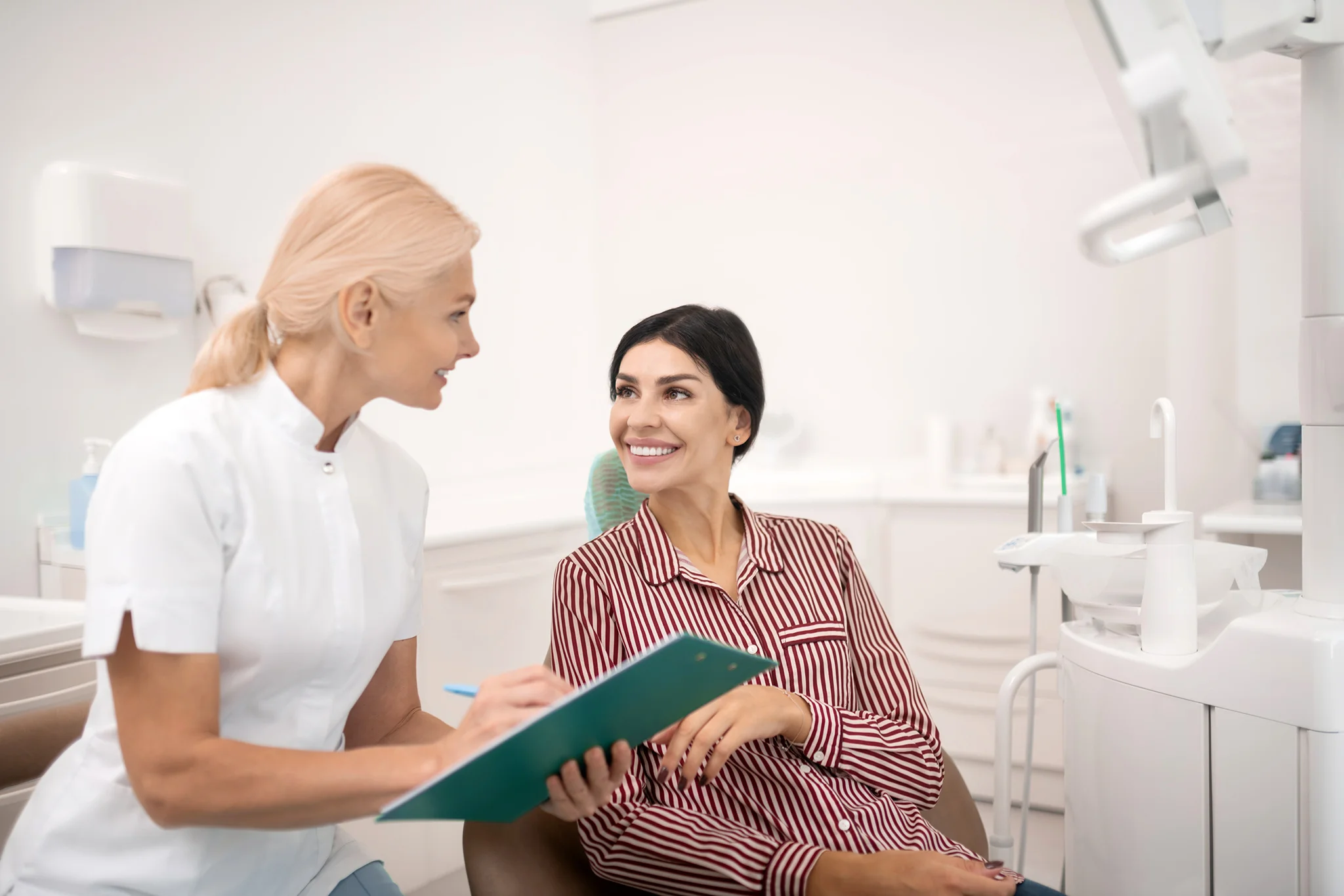 Dentist reviewing notes with a smiling patient in a bright treatment room